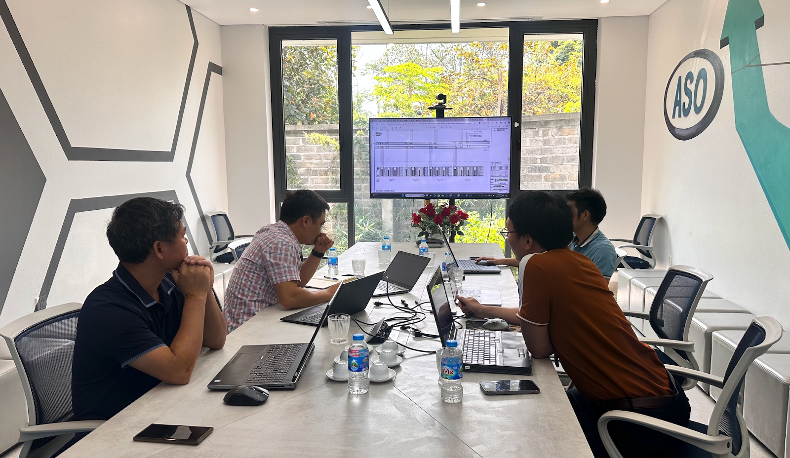 A group of people sitting at a table with laptopsDescription automatically generated